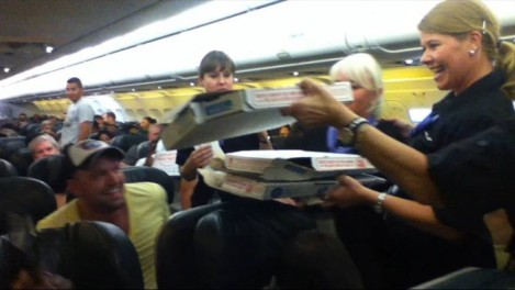 A Frontier Airlines flight attendant passes out pizza to passengers waiting out a delay in Cheyenne, Wyo. (Logan Marie Torres via KDVR.com)